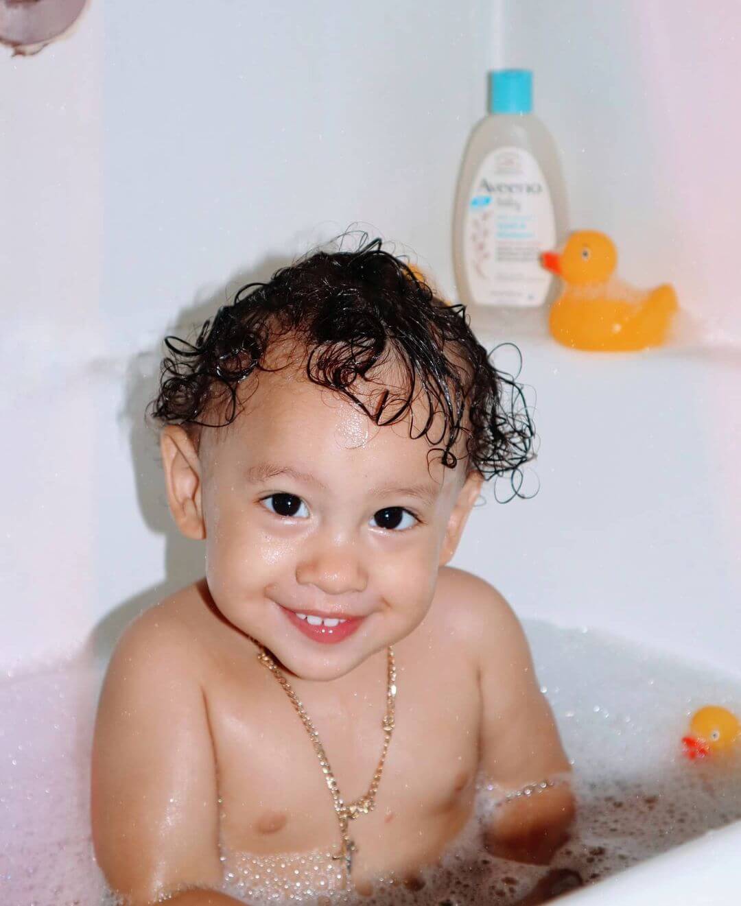Baby with curly hair taking a bath