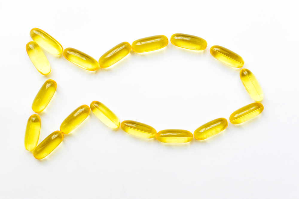 Fish oil capsules in yellow on a white background. Health care, nutritional supplements for athletes. The benefits of Omega 3 and capsules for the beauty of hair and skin.