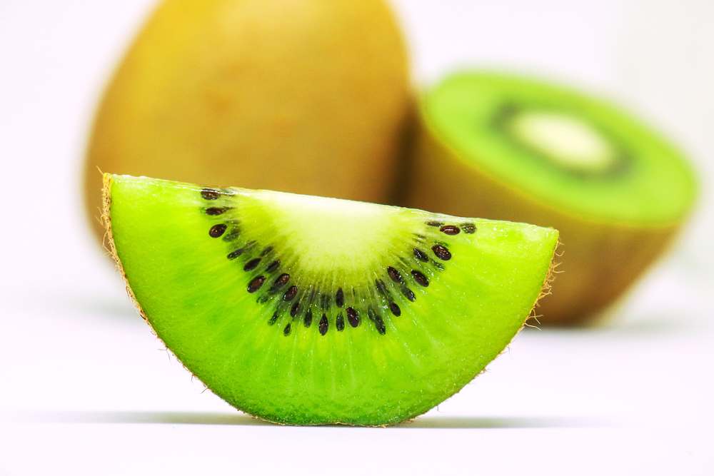 kiwi fruit sliced open on a white surface.