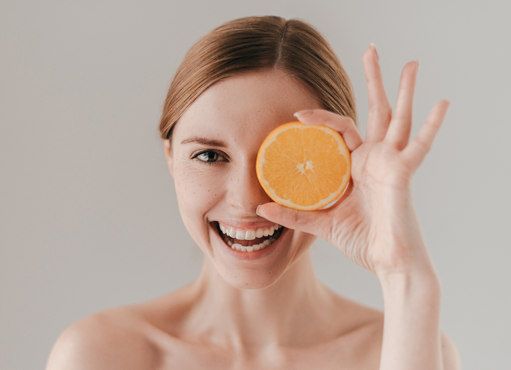 woman holding vitamin C-rich orange slice.