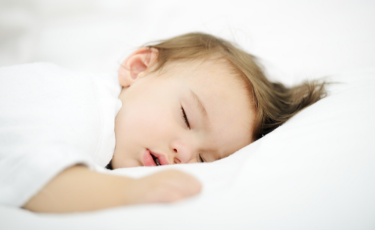 Toddler sleeping surrounded by white sheets