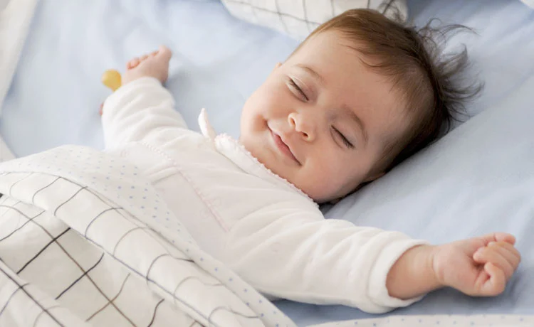 Smiling Baby Sleeping on a Blue Sheet